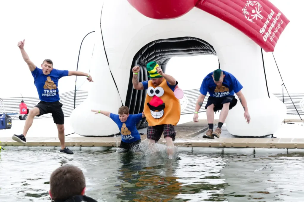 People jumping into icy water during polar plunge event wearing potato costumes