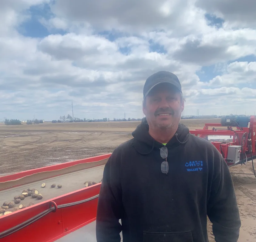 Farmer standing beside farm equipment outdoors