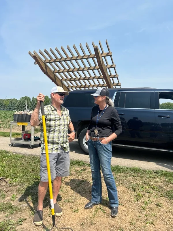People measuring field area beside farm vehicle