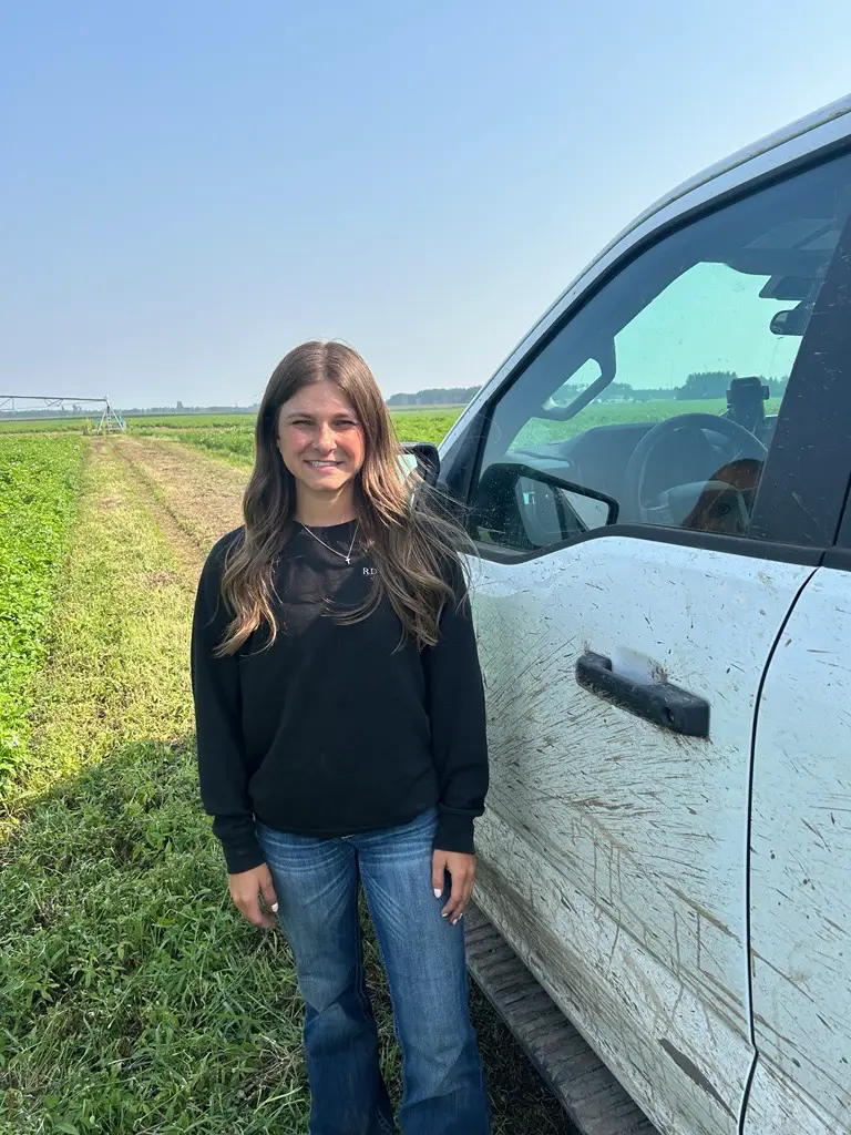 Young woman standing beside white pickup truck in field