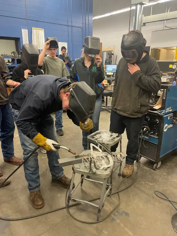 Worker using welding tools in industrial training workshop