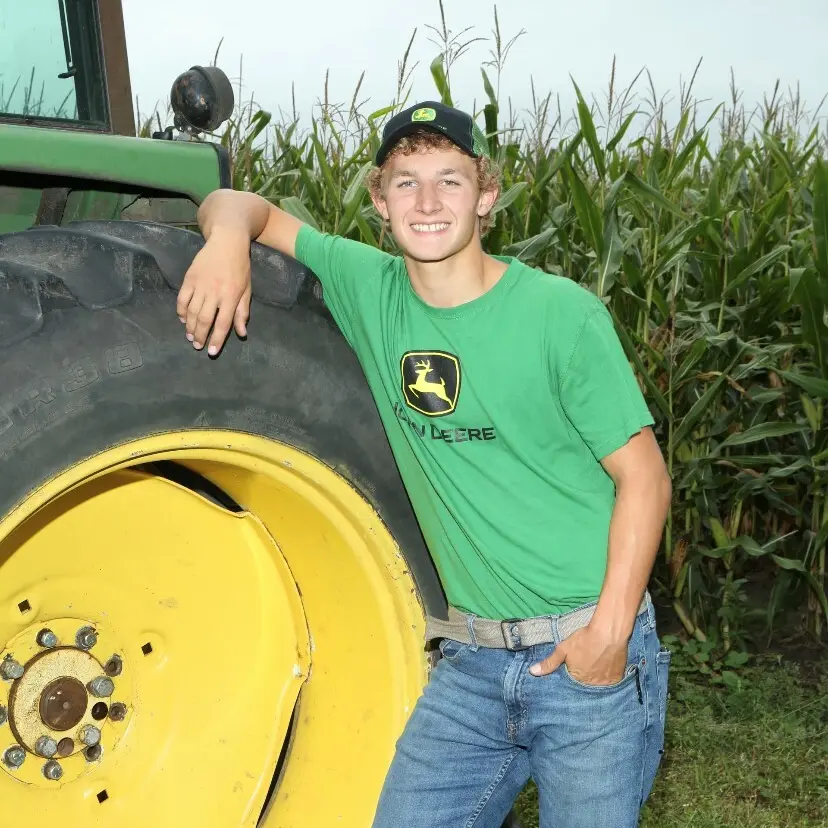Adam Lange in John Deere branded entire, next to a John Deere tractor