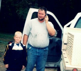 Adult standing beside child near farm vehicle