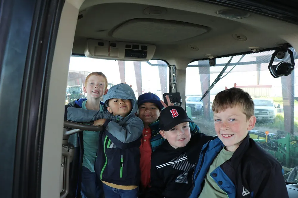 Children sitting inside farm vehicle cab