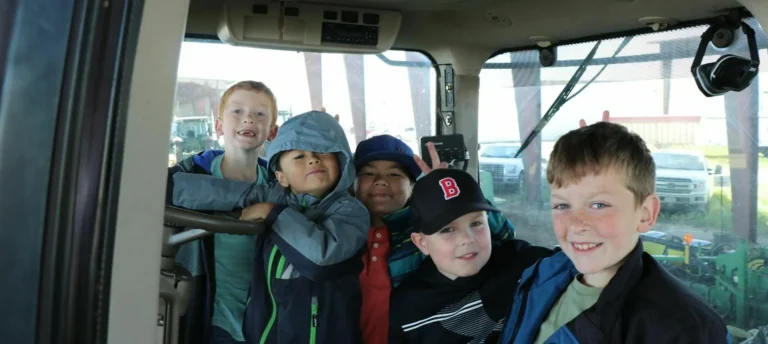 Children sitting inside farm vehicle cab