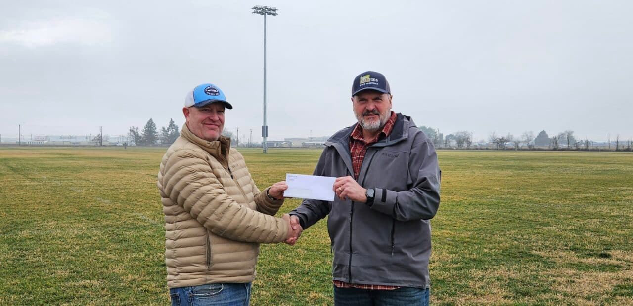 Two people shaking hands outdoors in field