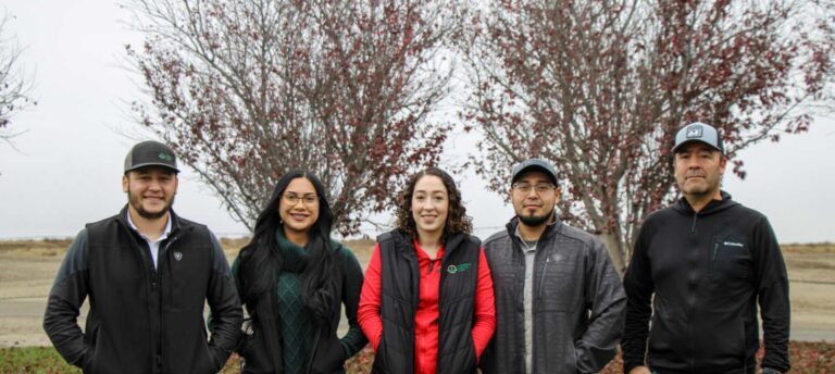 Group posing outdoors beside flowering trees