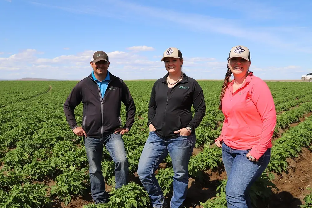 Three people standing together outdoors in field
