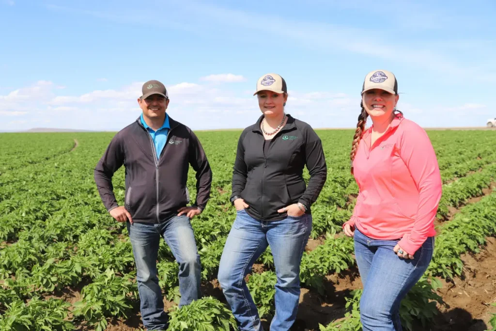 Three people standing together outdoors in field