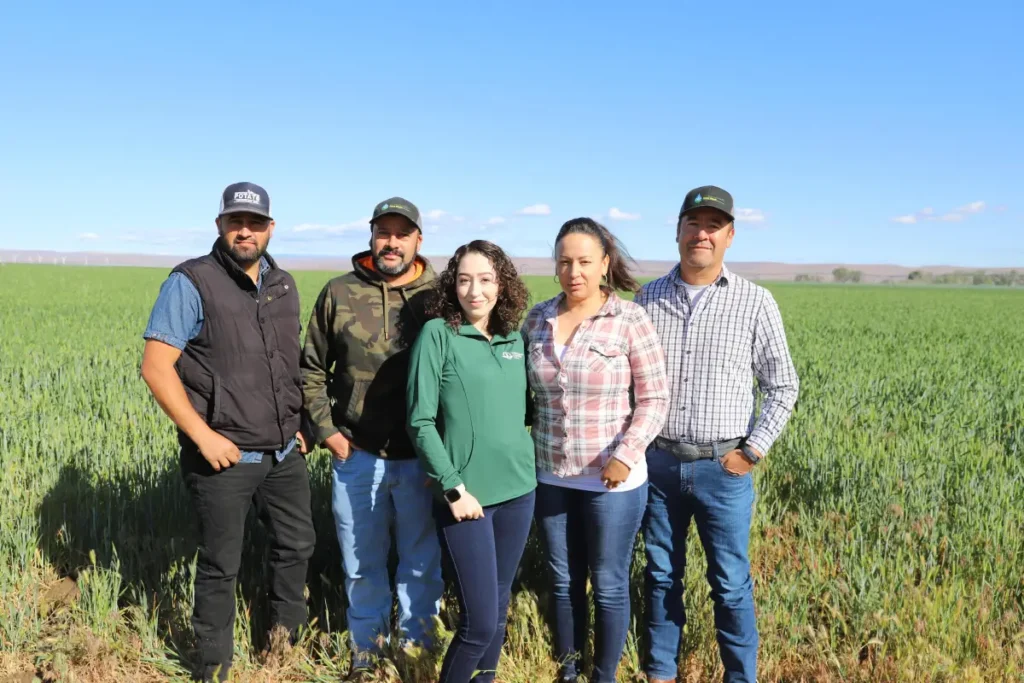 Group posing together outdoors in front of crops