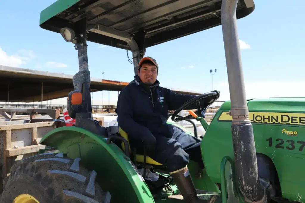 Person driving tractor near open-sided structure