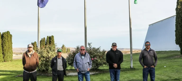 Veterans standing in front of flag poles.