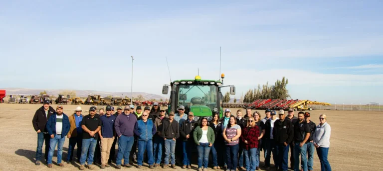 Group gathered outdoors in front of tractor