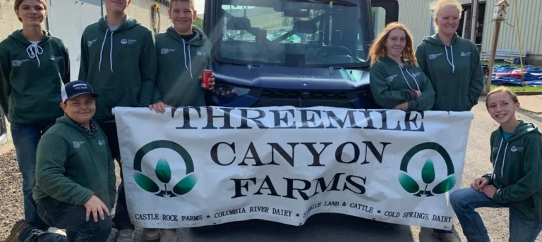Group holding Threemile Canyone Farms banner outdoors