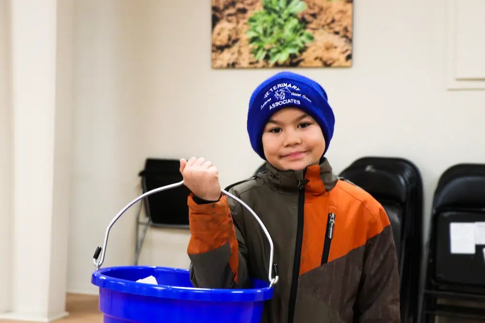 Child holding blue bucket indoors